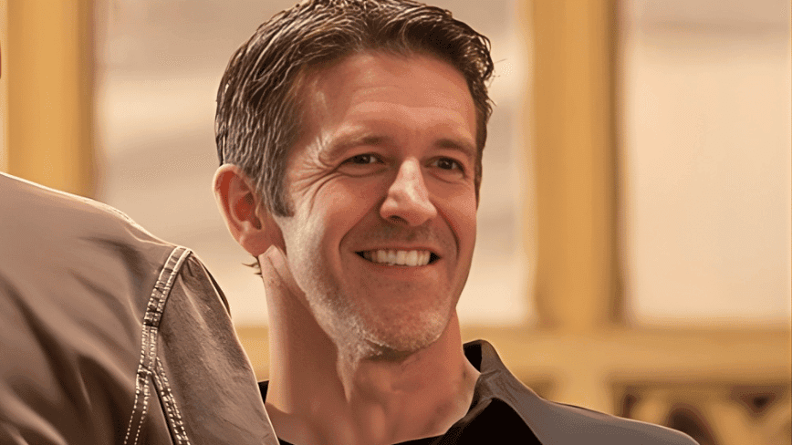 Tim Cook portrait with Apple logo backdrop, professional corporate setting